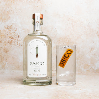Bottle and glass of 58 AND CO LONDON DRY Gin on a textured surface