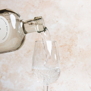 58 and CO London Dry Gin bottle being poured into a glass on a light marble surface