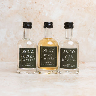 Three miniature bottles of 58 Co. Vodka Martini, Wet Martini, and Gin Martini on a textured surface.