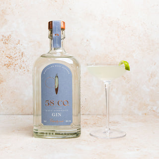 Bottle of 58 AND CO NAVY STRENGTH GIN with a gimlet cocktail on a light background