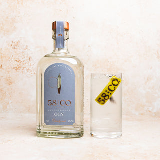 Bottle of 58 AND CO NAVY STRENGTH GIN with a glass on a light background