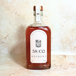 Bottle of 58 and CO ready to drink negroni cocktail  on a light stone background