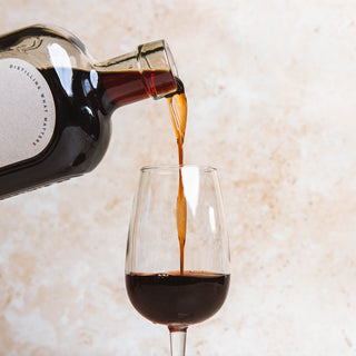 58 and co double sloe gin being poured from a bottle into a glass with a neutral background