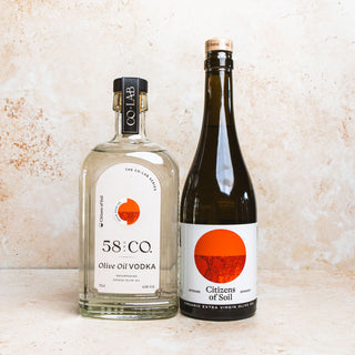 Two bottles of  58 and CO Olive Oil Vodka spain edition and Citizens of Soil Extra Virgin Olive Oil on a textured beige background