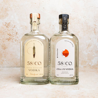 Two bottles of 58 and co vodka and olive oil vodka on a textured surface