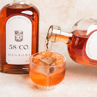Bottle of 58 AND Co Negroni being poured into a glass with ice.