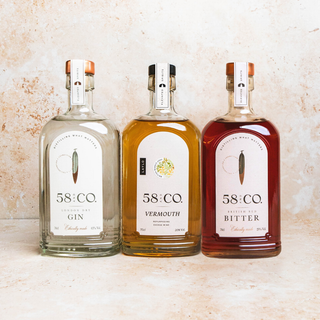 Three bottles of 58 and CO London Dry Gin, Bianco Vermouth and Red Bitter on a textured surface