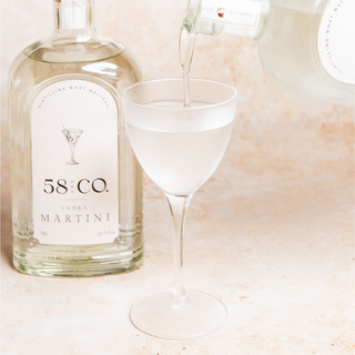 Bottle of 58 and Co. Vodka Martini being poured into a glass on a light background