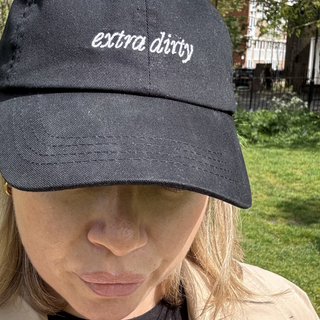 Person wearing a 58 and CO black cap with 'extra dirty' text outdoors.