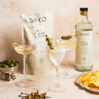 58 and CO House Pour Gin bottle and refill pouch with cocktails, and snacks on a table 