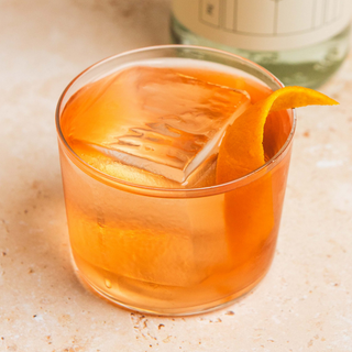 Negroni cocktail with an orange twist in a glass on a light surface