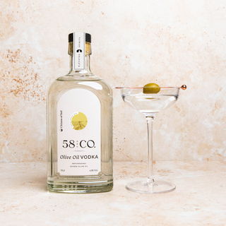 Bottle of 58 and CO Olive Oil Vodka with a martini glass on a textured surface