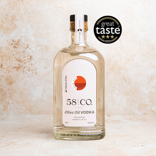 A bottle of 58 and CO. Olive Oil Vodka on a textured beige stone background, featuring a black and white 'great taste 2025' award badge overlay in the top right.