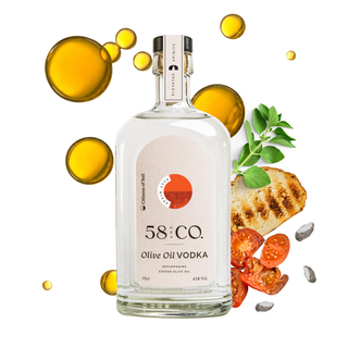 A bottle of 58 and CO. olive oil vodka centered on a white background, surrounded by floating golden oil droplets, sliced tomatoes, a grilled bread slice, green herbs, and small clay stones.