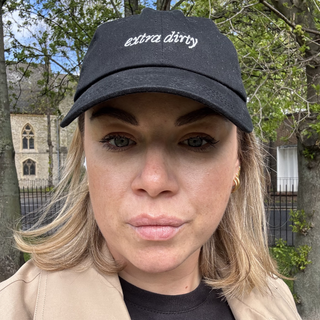 Person wearing a 58 and CO black cap with 'extra dirty' text outdoors.