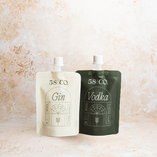 Two mini travel pouches labeled 'Gin' and 'Vodka' from 58 and Co House Pour on a textured beige background.